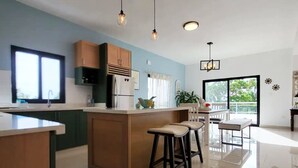 A modern kitchen with a central island, bar stools, pendant lighting, and a view of the outdoors. - Luxury Apt w/ Pool 5-min Walk to Beach & Ocean World (Cofresi)