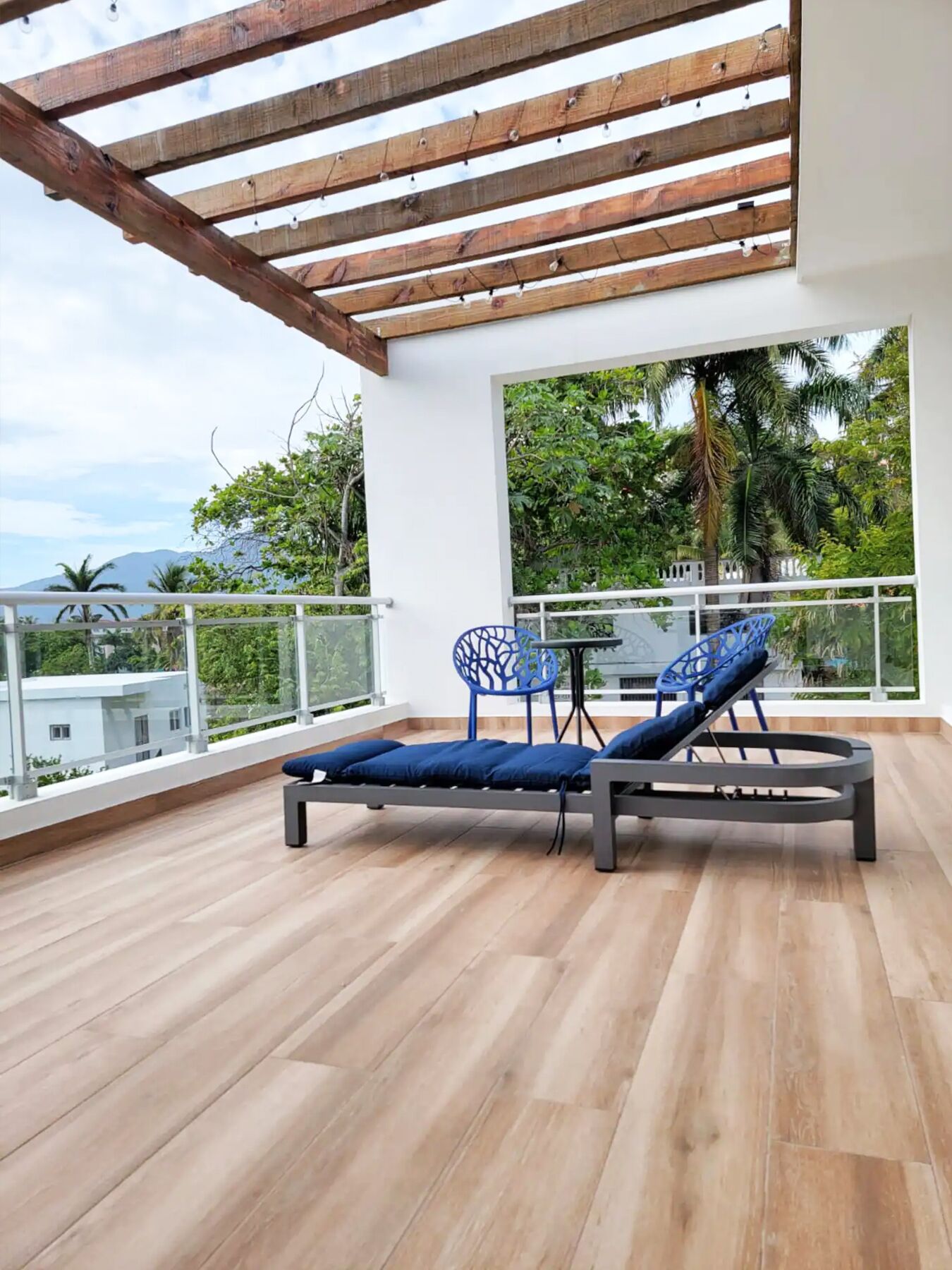 Un balcon doté d’un plafond en bois, de deux chaises bleues et d’une table.