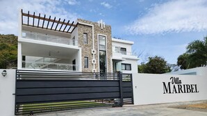 A modern villa with a stone facade, a balcony, and a gated entrance. - Luxury Apt w/ Pool 5-min Walk to Beach & Ocean World (Cofresi)