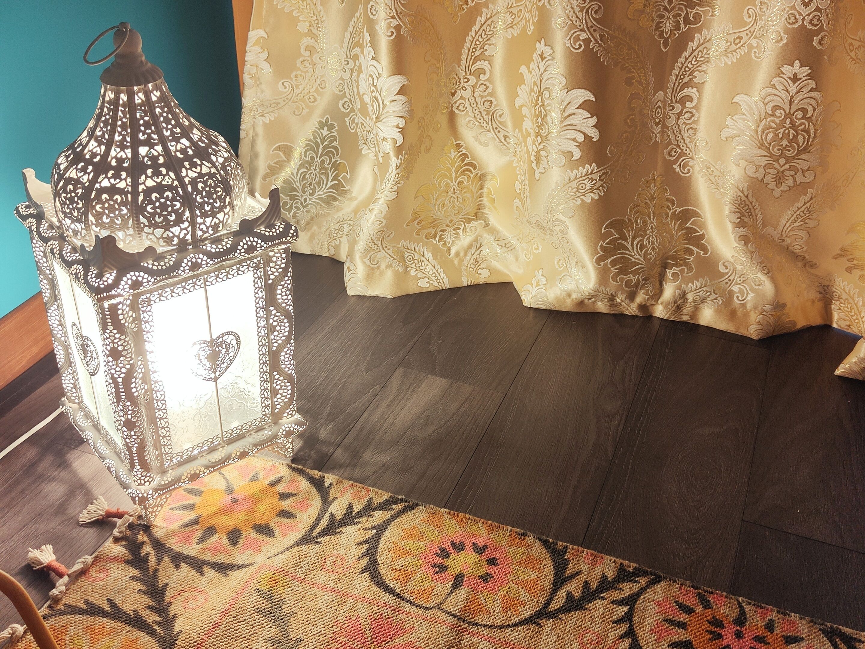 A room with a patterned rug, a decorative lantern, and a curtain with floral designs.