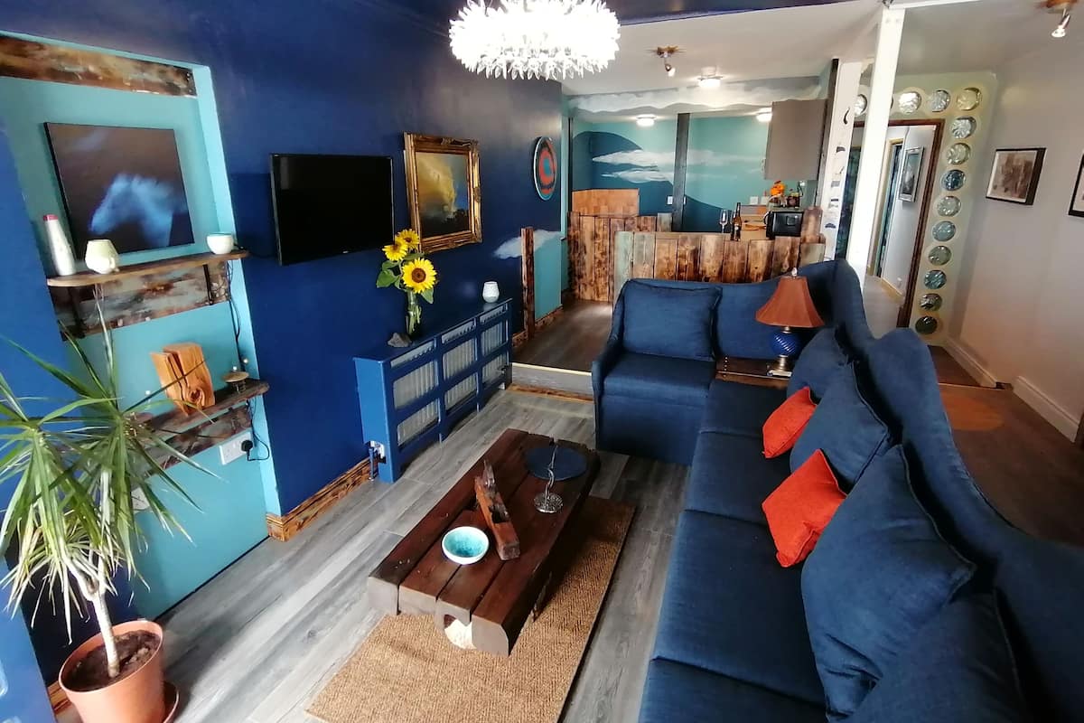 A living room with a blue sofa, a coffee table, a TV, and a wooden cabinet.