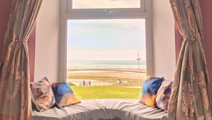 A room with a large window, a bed with pillows, and curtains. - Mourne Mountain Art Apartments (Newcastle)