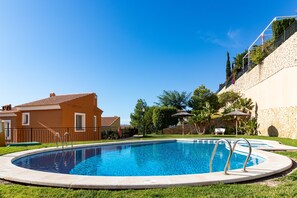 A swimming pool with a stone wall and a house in the background.