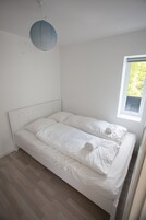 Una cama individual con ropa blanca en una habitación con techo inclinado y ventana.