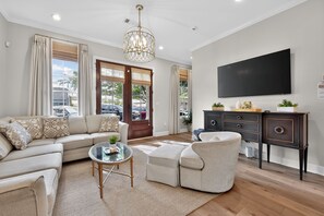 Uma sala de estar moderna com sofá, poltrona, mesa de centro e TV fixada na parede.