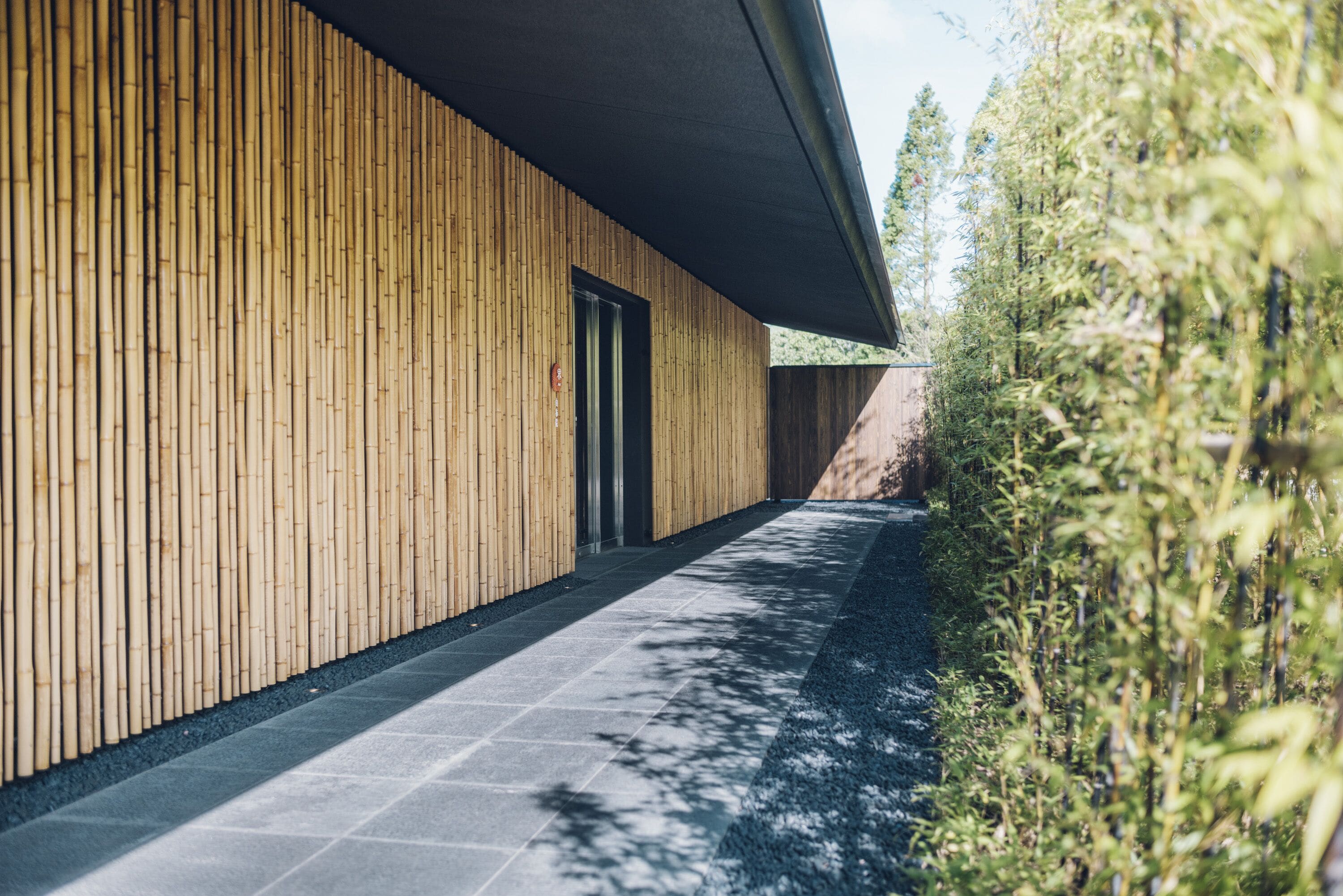 A modern building with a wooden exterior and a paved pathway leading to a door.