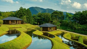 En traditionel japansk ryokan med to træbygninger, terrasserede rismarker og et bjerg i baggrunden.