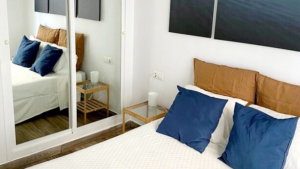 Ein Schlafzimmer mit Bett, Nachttisch, Spiegel und Bildern an der Wand.