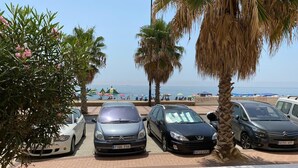 Ein Parkplatz mit mehreren Autos, Palmen und einem Strand im Hintergrund.