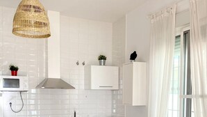 Eine moderne Küche mit weißen Schränken, einer eingebauten Mikrowelle, einer Waschmaschine und einem Essbereich mit Tisch und Stühlen.