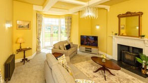 A living room with a sofa, TV, fireplace, and a view through a glass door.