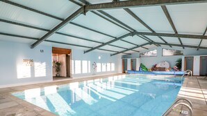 An indoor swimming pool with a clear ceiling, a lifebuoy, and a sign indicating the pool's depth.