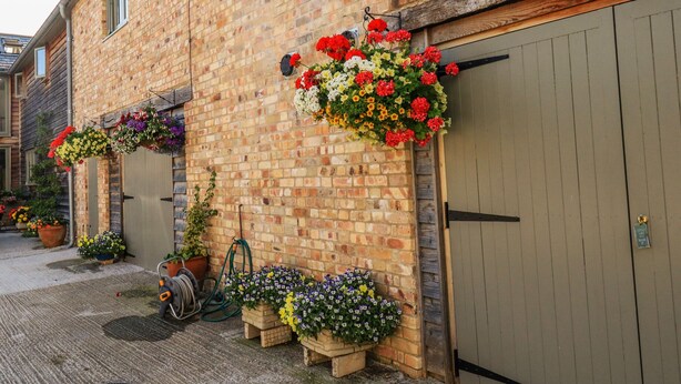 A brick building with flower boxes and a wooden door. - The Mews (Newton Abbot)