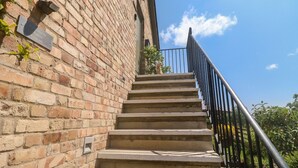 A brick building with a staircase leading to a balcony. - The Mews (Newton Abbot)