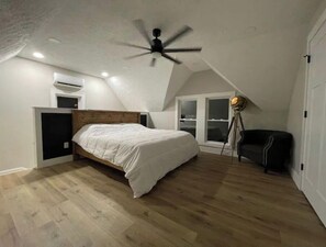 Cozy bedroom with a single bed, wooden headboard, and ceiling fan, offering a view of the outside through the window.