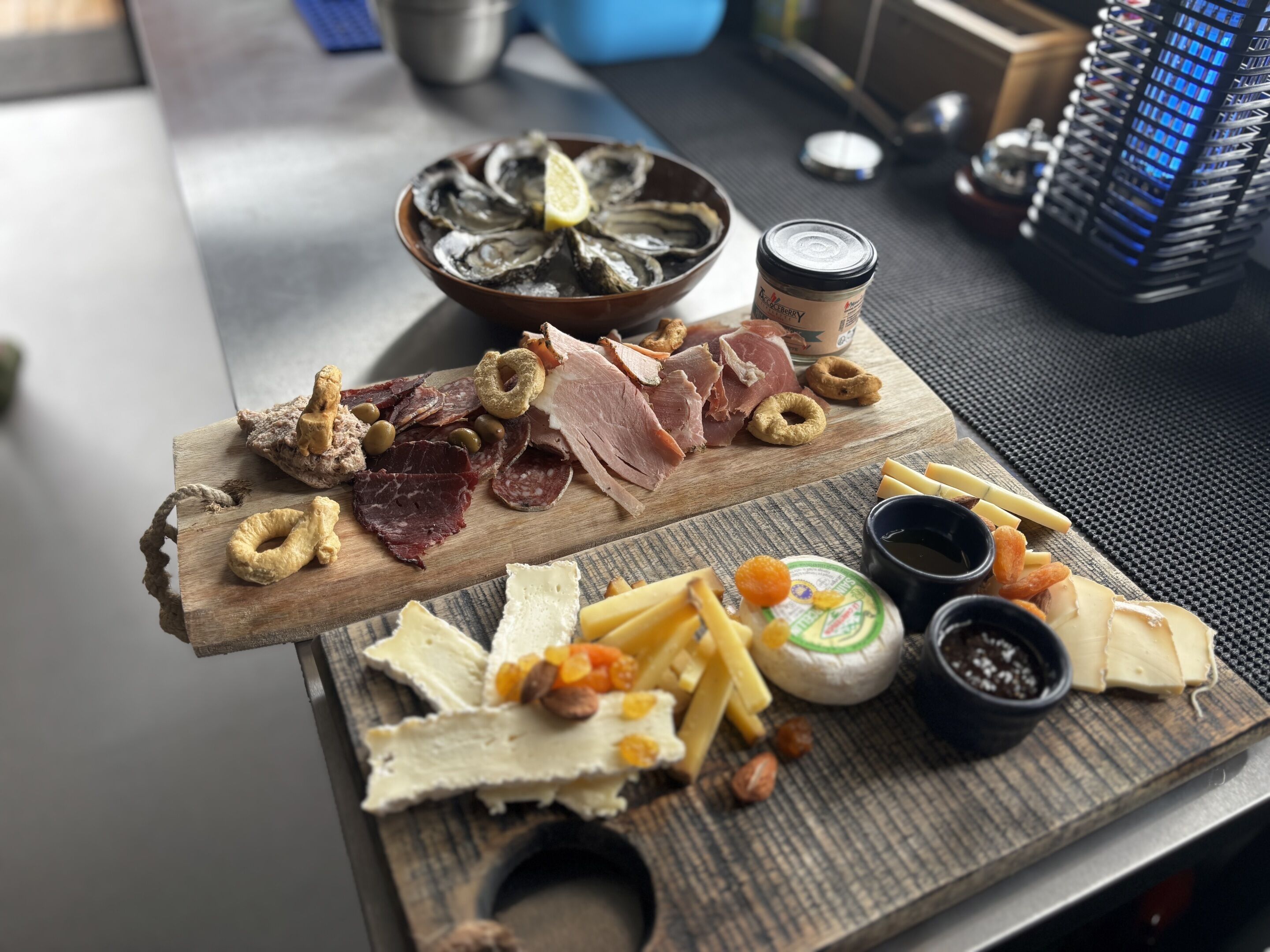 A wooden board with various cheeses, cured meats, and olives.