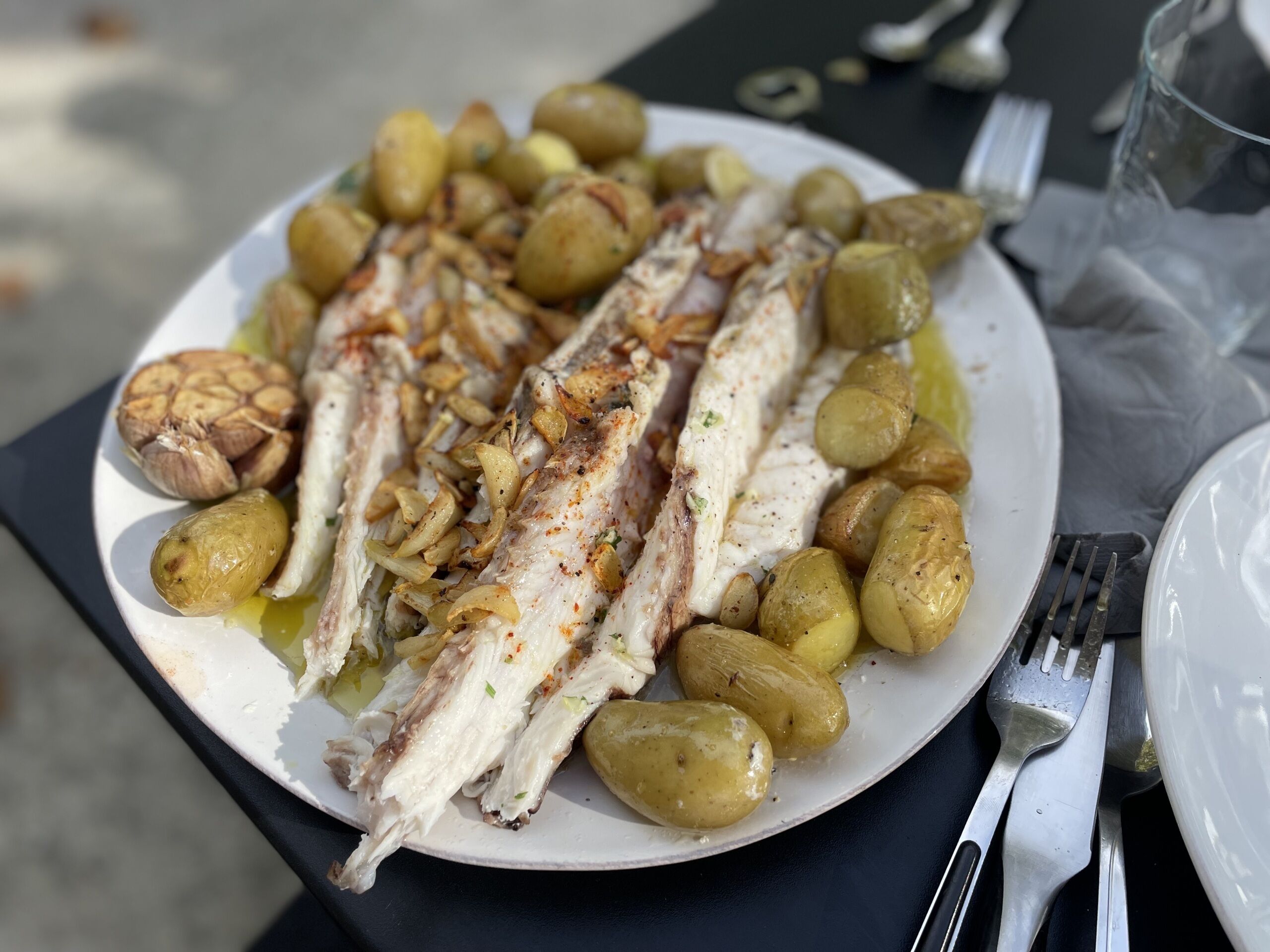 Ein Teller gegrillter Fisch und geröstete Kartoffeln.