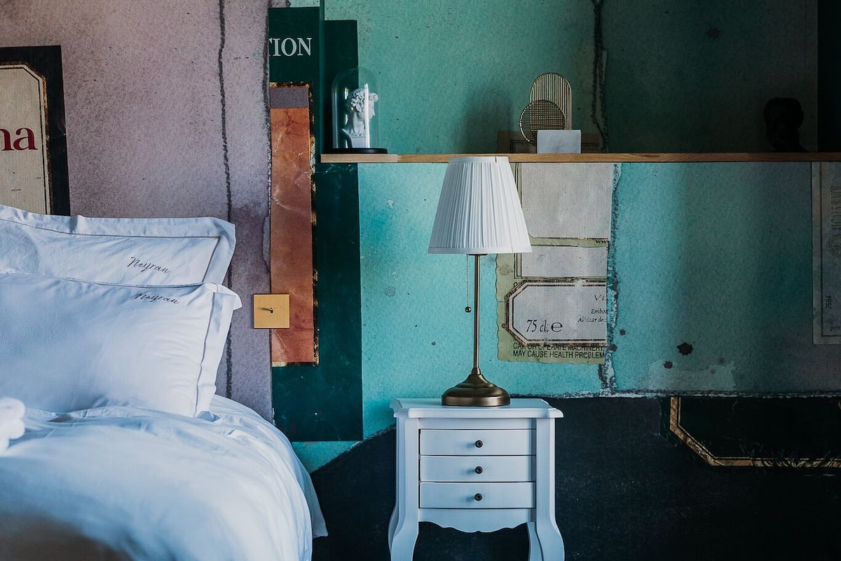Une chambre à coucher comprenant un lit, une table de chevet, une lampe et un mur orné d’une carte et d’une pancarte indiquant « Hyde Park, État de New York ».