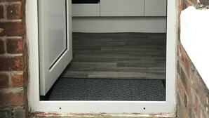 A narrow kitchen with white cabinets, a stainless steel range hood, and a black countertop. - Bright Spacious 3-bed With Office & Patio, Preston (Preston)