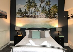 A bedroom with a bed, two bedside tables, a nightstand, a wall-mounted lamp, and a tropical beach mural. - Bright Spacious 3-bed With Office & Patio, Preston (Preston)