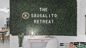 Une pièce avec un mur recouvert de verdure, un bureau, une chaise, une table de baby-foot et une petite plante.