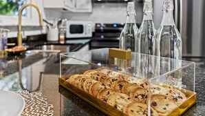 Un comptoir de cuisine surmonté d’une vitrine en verre contenant des biscuits et trois bouteilles.