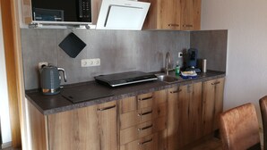 Una cucina accessoriata con forno a microonde, bollitore, macchina del caffè e bilancia digitale.