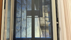 Ventana con barrotes y vista a un edificio.