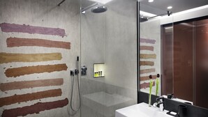 Un baño moderno con cabina de ducha de vidrio, un lavamanos blanco y un espejo que refleja la habitación.