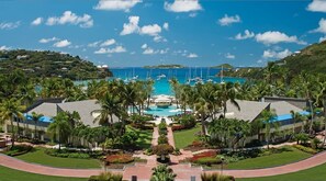 Ein Resort mit einem zentralen Pool, Palmen und Booten im Hintergrund.