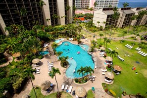 A resort with a central swimming pool, lounge areas, and a view of the ocean.