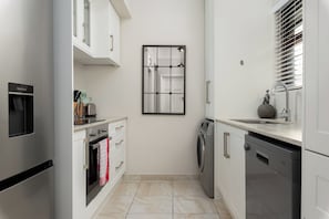 Una cocina compacta equipada con refrigerador, horno, lavavajillas y lavadora.