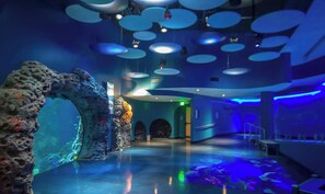 A spacious lobby with a large aquarium, modern lighting, and a clear exit sign.