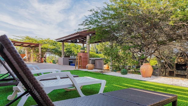 Een terras met buitenmeubilair, een pergola en een barbecue.
