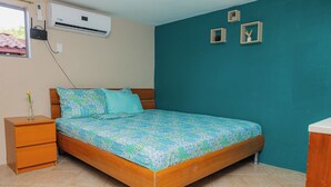 Een slaapkamer met een houten bed, teal muren, een klein nachtkastje en een raam.
