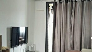 En moderne stue med et fladskærms-tv, en sofa, et sofabord og et spiseområde.