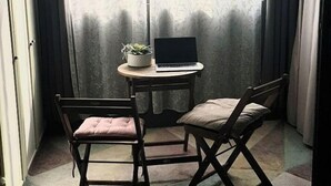 Et lille rum med et bord, to stole, en bærbar computer og en potteplante.