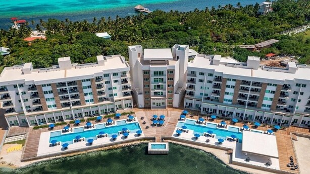 Un resort con varias piscinas, un patio central y vista al océano.