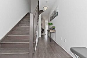 Staircase leads to an upper level, with a cozy reading nook featuring a table, vase, and books.