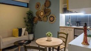 Uma sala de estar moderna com uma mesa de madeira redonda, um sofá e um elemento decorativo na parede.