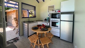 Cocina compacta con comedor, electrodomésticos integrados y vistas a un patio exterior.