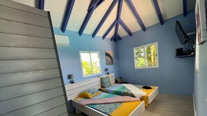 Un dormitorio con dos camas, una ventana y un techo con vigas a la vista.
