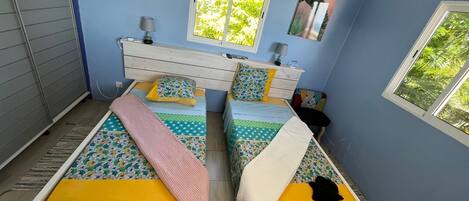 A bedroom with two beds, a dresser, two lamps, and two windows.