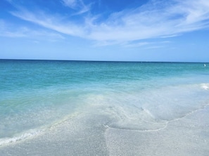 Une plage à l’eau turquoise et limpide, bordée d’un rivage sablonneux.