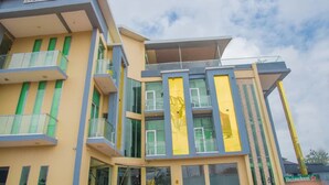 Un hotel moderno con fachada amarilla, varios balcones y ventanas grandes.
