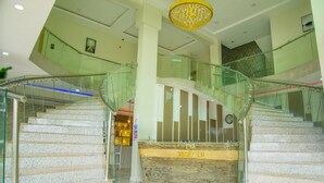 Una imponente escalera con barandas de vidrio que lleva a una zona de recepción.