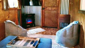L’intérieur d’un chalet chaleureux, avec une cheminée, des murs en bois et un canapé bleu.