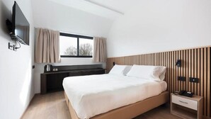 A modern hotel room with a large bed, a TV mounted on the wall, a bedside table with a lamp, and a window with curtains. - Moon Palace Hotel  (Arese)