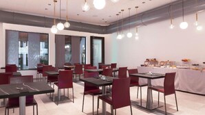 A modern dining area with multiple tables and chairs, large windows, and hanging pendant lights. - Moon Palace Hotel  (Arese)