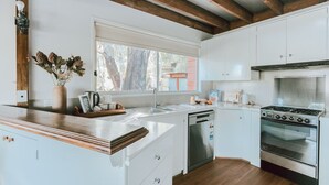 Una cocina moderna con armarios blancos, estufa de acero inoxidable y encimera de madera.